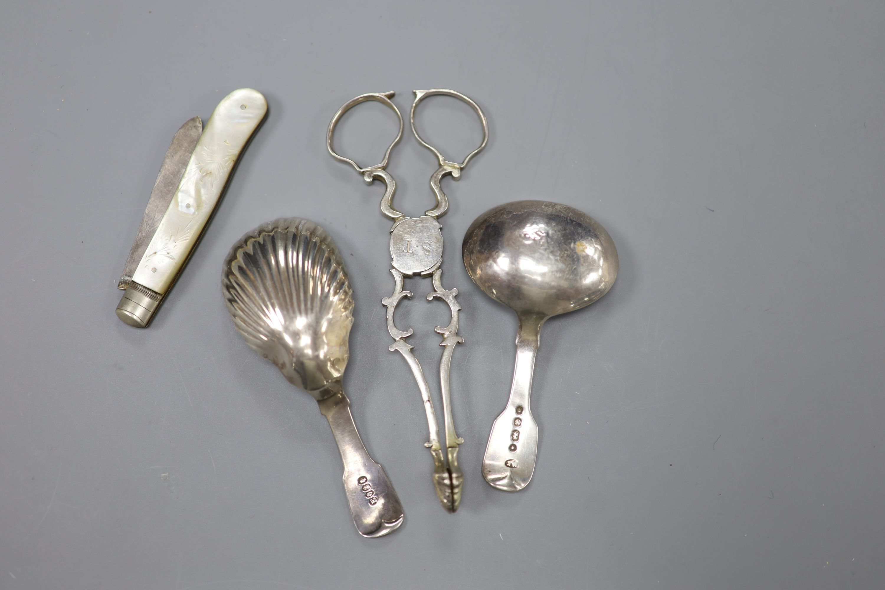 A pair of 18th century silver sugar nips, two later silver caddy spoons and a mother of pearl and silver fruit knife.